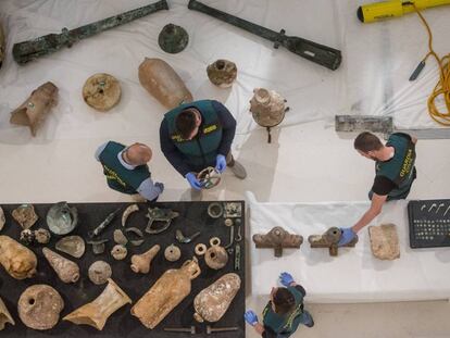 Agentes de la Guardia Civil revisan objetos arqueológicos expoliados.
