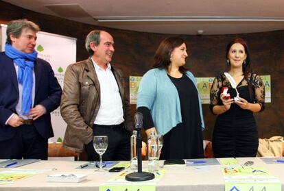 Dolores Redondo sostiene la Pluma de Plata en presencia de los organizadores de la Feria del Libro de Bilbao.