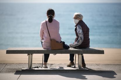 Dos mujeres se sientan frente al mar, en Barcelona, en una foto de archivo.