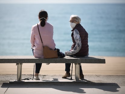 Dos mujeres se sientan frente al mar, en Barcelona, en una foto de archivo.