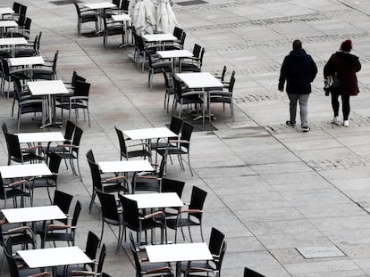 Dos personas caminan por la Plaza del Castillo, en Pamplona, al lado de mesas de las terrazas vacías, el 22 de octubre.