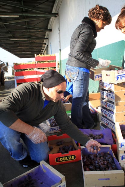 Dos personas tantean la fruta tirada en el exterior de Mercamadrid.