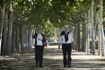 Dos personas, protegidas con mascarillas, pasean por Sevilla. 
