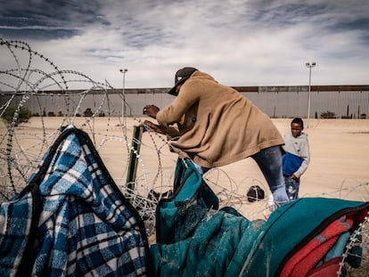 Dos migrantes cruzan un alambrado colocado por la patrulla fronteriza en El Paso (EE UU), el 20 de octubre de 2023.