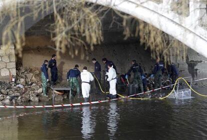Agentes de Policía Científica buscan restos humanos debajo del puente de la Victoria.