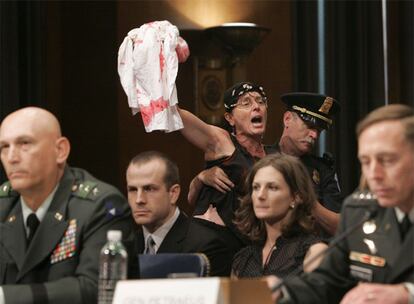 Un policía expulsa del Senado a una manifestante contra la guerra durante la comparecencia de Petraeus.