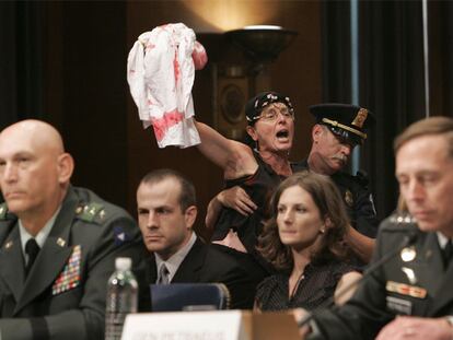 Un policía expulsa del Senado a una manifestante contra la guerra durante la comparecencia de Petraeus.