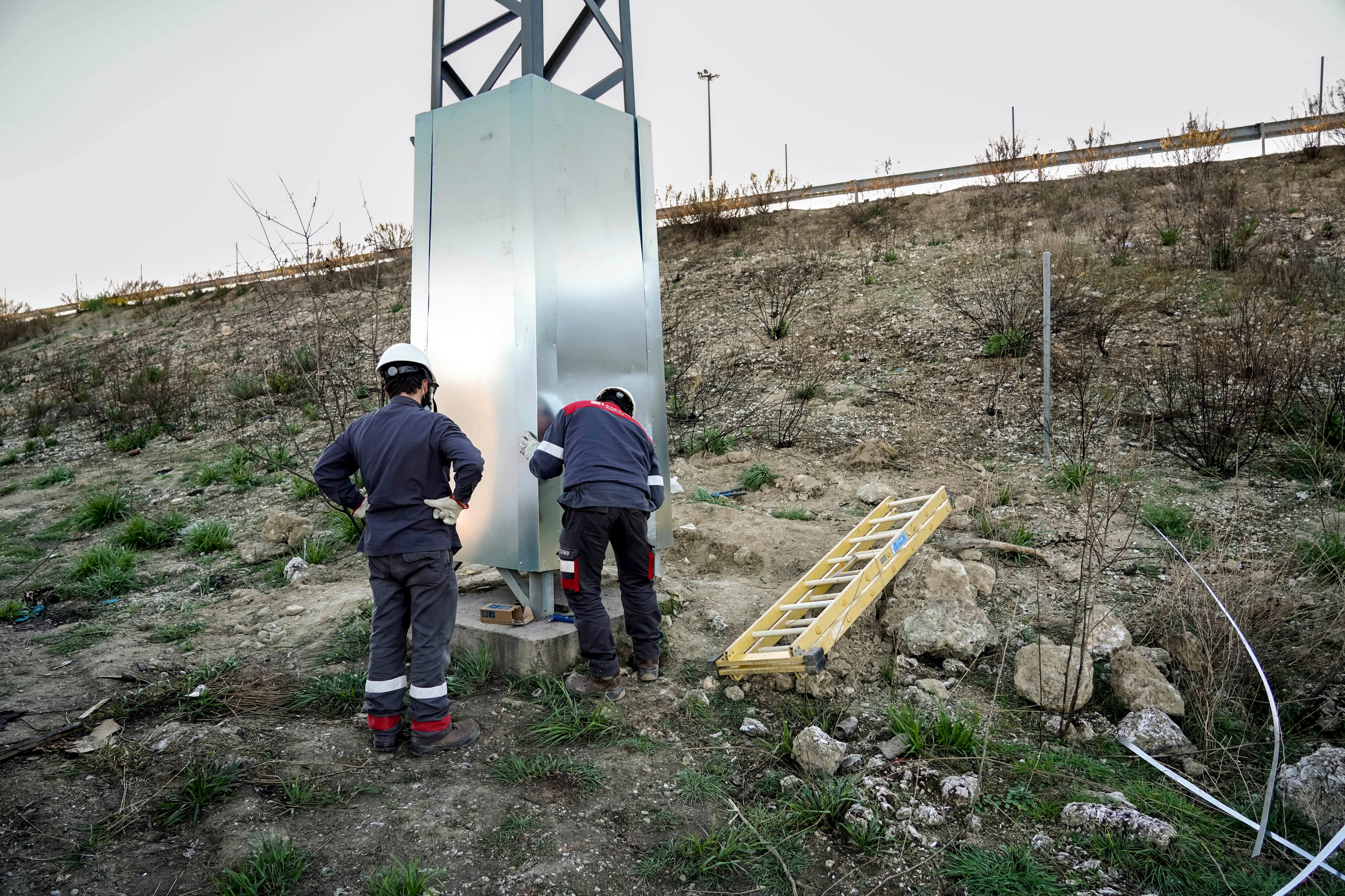 Dos operarios de una subcontrata de Naturgy cubren con unos paneles una torre de la luz para evitar manipulaciones del suministro