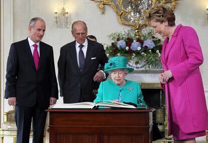 La reina Isabel II firma en el libro de honor durante su visita a Irlanda.