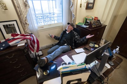 Un partidario del presidente de Estados Unidos, Donald J. Trump, se sienta en el escritorio de la presidenta de la Cámara de Representantes de Estados Unidos, Nancy Pelosi