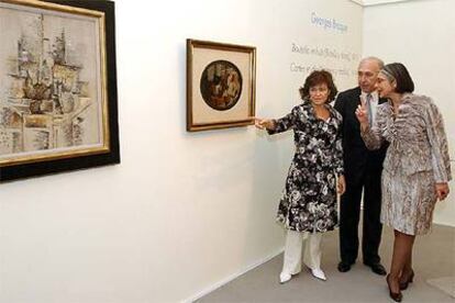 Carmen Calvo, Juan Manuel Urgoiti y Ana Martínez de Aguilar (de izquierda a derecha), durante la presentación de <i>Botella y fruta</i>s (1911), a la izquierda, y <i>Naipes y dados </i><b>(1914), de Braque.</b>