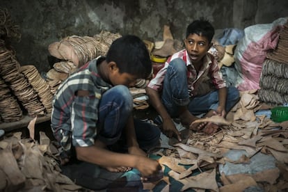 Rakib Mridha (a la derecha) tiene 12 años y trabaja desde los nueve en un taller que fabrica suelas de cuero para zapatos. Maneja cuchillas y herramientas punzantes para cortar el material que sujeta con sus pies descalzos. Por eso, se hace cortes en los dedos a menudo. Realiza una jornada laboral completa por 1.500 takas (17,5 euros) y sólo libra media jornada los viernes. En Bangladesh está prohibido por ley que los menores de 14 años trabajen; pero además, esta tarea está vetada a los que tienen entre 15 y 17, pues el procesado del cuero esta incluido en una lista de 38 oficios peligrosos a los que ningún menor de edad puede dedicarse.