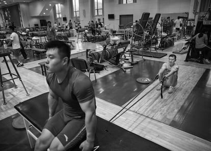 El entrenador del levantador de pesos Yang Zhe, que compite en los 105 kg, sujeta las bandas de resistencia durante una sesión previa a los Juegos Olímpicos de Rio, en Pekín, China. El equipo chino para las Olimpiadas cuenta con 6 hombres y 4 mujeres, la cuota máxima fijada para el equipo combinado en las dos últimas competiciones mundiales.