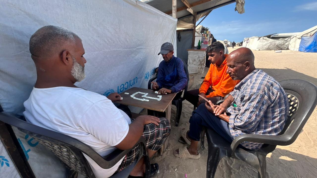 Mohammed Hamdan Abu Shahab, de 40 años, juega a un juego de mesa con su hijo Naim y sus amigos en la playa de Gaza, el 9 de octubre. Es la primera vez en cinco meses que se siente lo suficientemente seguro como para disfrutar de este sencillo placer.
