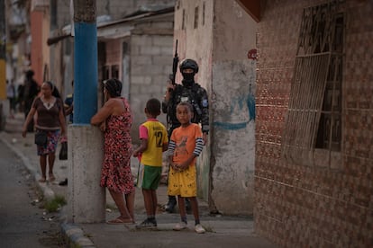 Resguardados por un policía, una señora y dos niños observan el operativo de control, en Esmeraldas.