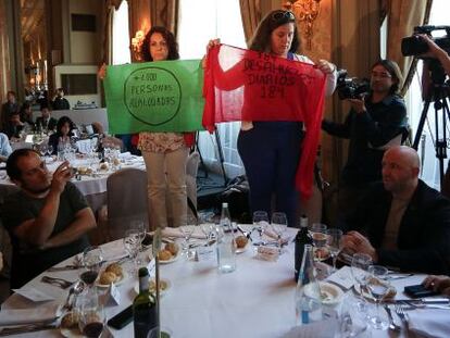 Dos activistas de la PAH despliegan unas pancartas en un almuerzo con Cañete. A la izquierda, David Fernández y, a la derecha, el concejal del PP de Barcelona Javier Mulleras y el diputado popular Rafa Lopez.