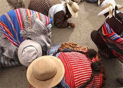 Mujeres indígenas buscan pepitas de oro en una calle de El Alto, ciudad dormitorio de La Paz.