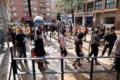 Decenas de vecinos esperan su turno para el reparto de agua potable en la localidad valenciana de Paiporta, este jueves.