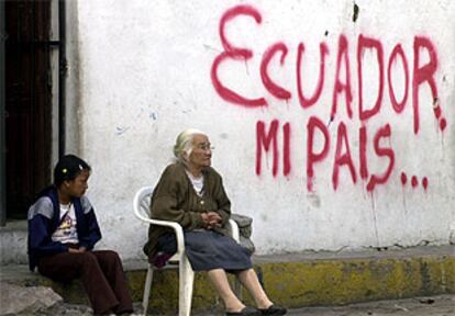 Una anciana y una niña, junto a una pintada en Quito.