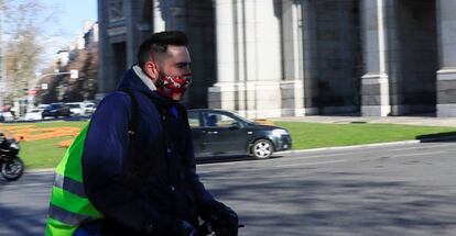 Un hombre circula en un patinete eléctrico por la calzada en la rotonda de la Puerta de Alcalá en Madrid.