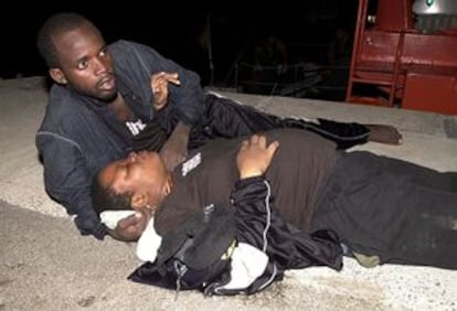 Una pareja de inmigrantes cuya mujer está en avanzado estado de gestación espera en el muelle de Gran Tarajal la llegada de una ambulancia.