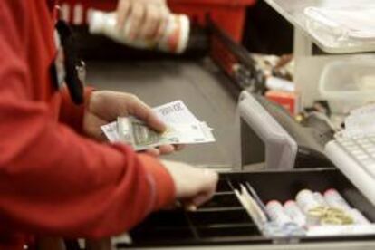 En la imagen, una cajera de un supermercado Rimi devolviendo cambio en euros a un cliente en Riga (Letonia). EFE/Archivo