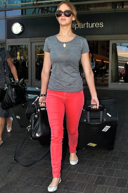 La actriz estadounidense Jennifer Lawrence con pantalón rojo, camiseta básica en gris y bailarinas en el aeropuerto de Los Ángeles.