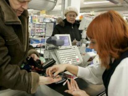 Una cajera ayuda a un cliente a contar las monedas de euro en un supermercado. EFE/Archivo