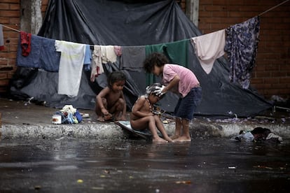 Criança ajuda outra a tomar banho aproveitando a chuva no acampamento que suas famílias montaram, em frente ao INDI (Instituto Paraguaio do Indígena, na tradução) em Assunção, para protestar exigindo mais terras.