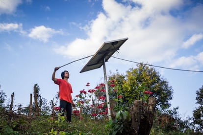 Un joven junto a un panel solar en una aldea de Tailandia.