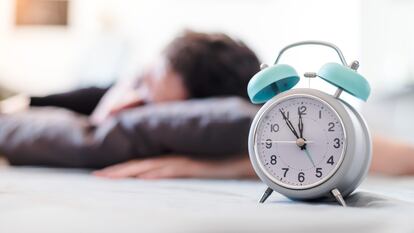 Un joven descansa junto a un despertador.