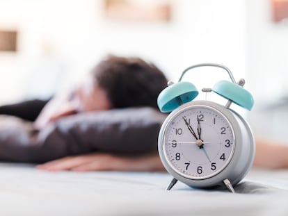 Un joven descansa junto a un despertador.