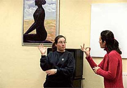 La profesora del curso de lenguaje de sordos (a la derecha) enseña los signos a una de las alumnas.