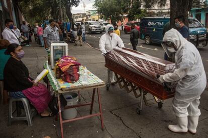 Dos empleados funerarios trasladan el féretro de una víctima de coronavirus, en Ciudad de Guatemala (Guatemala).