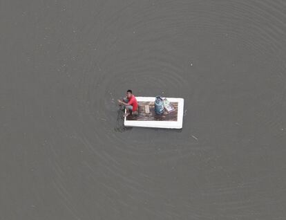 Un joven subido a una balsa improvisada trata de recoger parte de los suministros lanzados desde un helicóptero militar en la provincia de Pahum, al norte de Tailandia, una de las zonas que ha sufrido las mayores inundaciones de las últimas décadas.