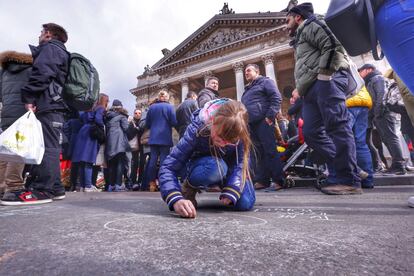 Una niña pinta con una tiza en el suelo de la plaza de la Bolsa de Bélgica en homenaje a las víctimas de los atentados.