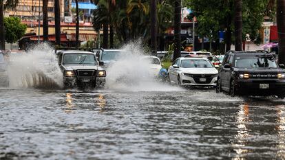 Vehículos transitan por una calle inundada en Acapulco, Guerrero, debido a las lluvias provocadas por el huracán Hilary.