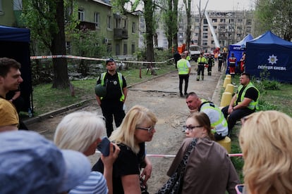 Un grupo de personas espera noticias sobre desaparecidos que permanecen debajo de los escombros junto a un edificio bombardeado por Rusia en Kiev.