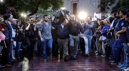 Un hombre carga una urna en el exterior de un colegio electoral en Barcelona.