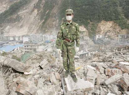 Un militar chino descansa sobre los restos de uno de los edificos desplomados en Bechuan.