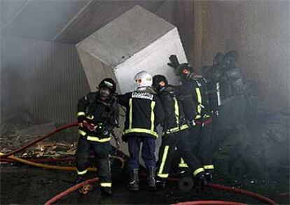 Los bomberos, ayer, luchaban contra el fuego en el interior de la industria incendiada en el polígono Pla de la Vallonga.