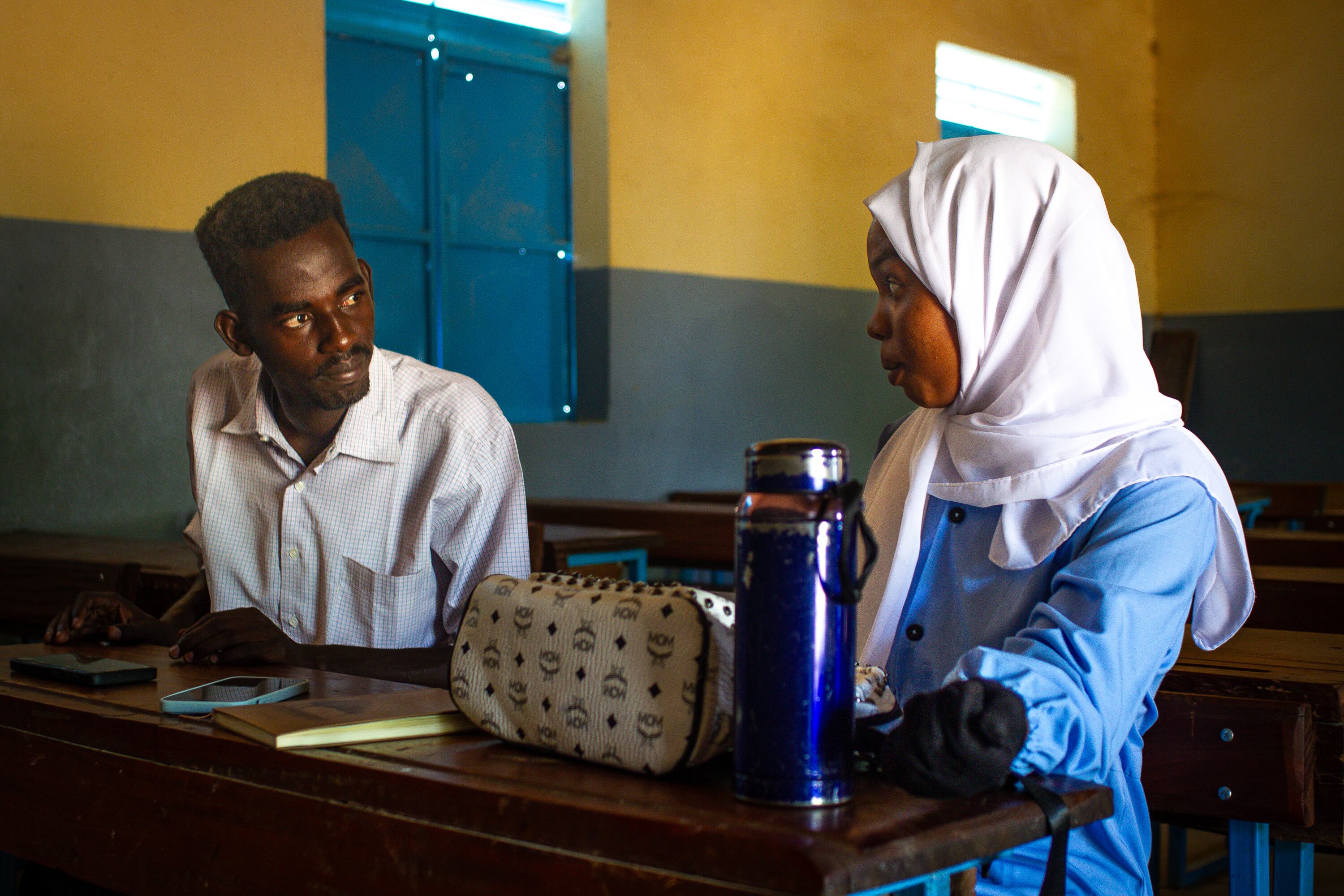Amar Adam charla con Khadija Hamed, estudiante de 18 años del instituto de secundaria del campo de refugiados de Farchana, en el este de Chad, en diciembre de 2025.