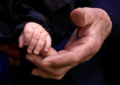 Un abuelo le da la mano a su nieto.