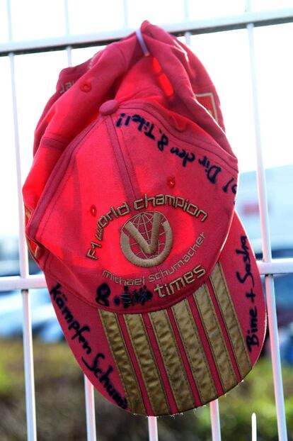 Una gorra roja cuelga de la valla con mensajes de ánimo y felicitaciones para Schumacher 