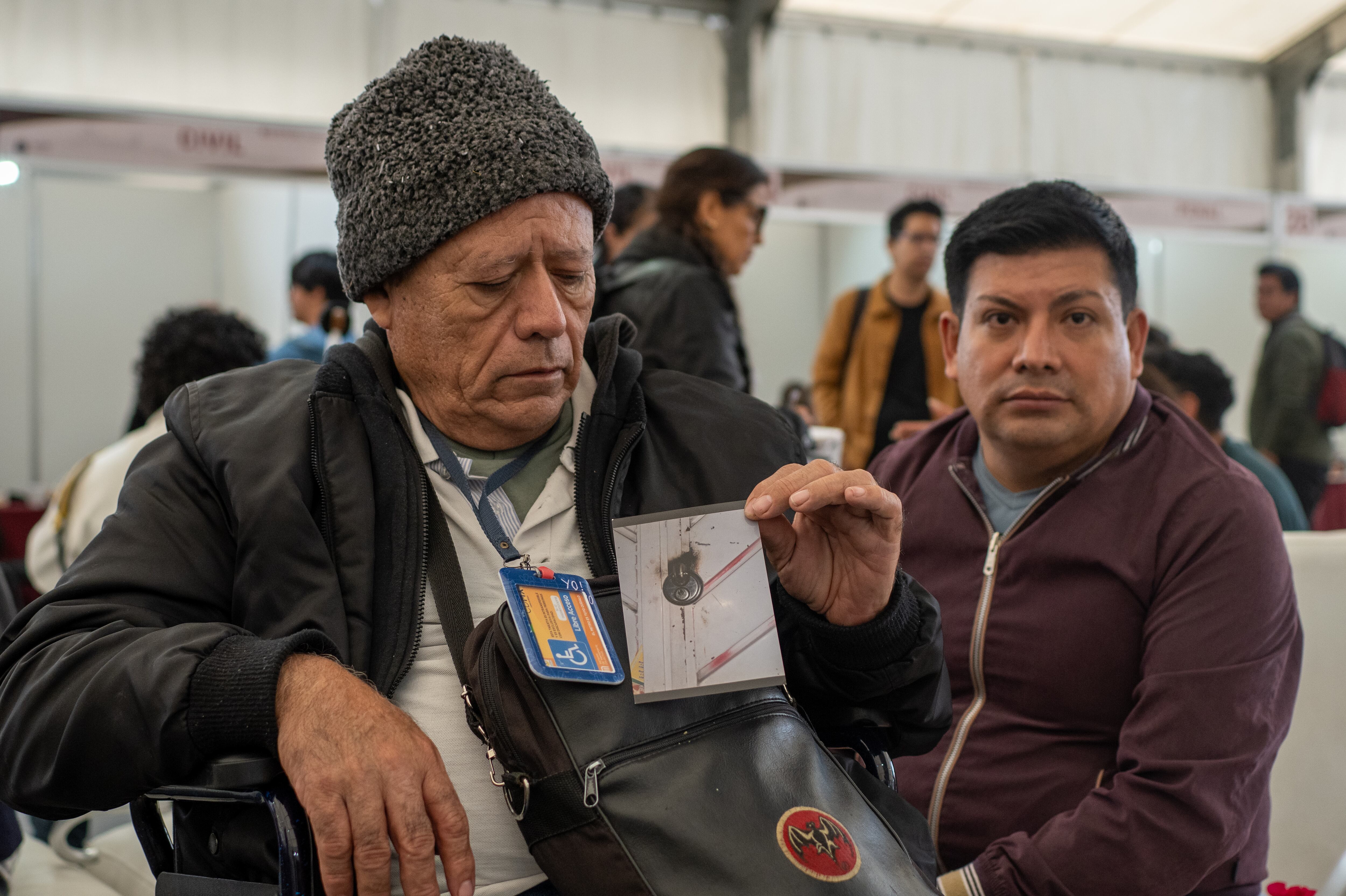 Alfredo Arellano y su hijo Marco muestran una fotografía de la cerradura de su vivienda alterada, el 24 de agosto en el Zócalo de Ciudad de México.