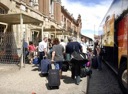 Decenas de viajeros con sus maletas tras llegar en autobús a la estación de tren de Aranjuez.