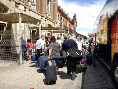 Decenas de viajeros con sus maletas tras llegar en autobús a la estación de tren de Aranjuez.