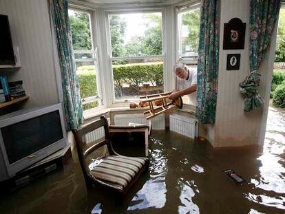 Un vecino de Tewkesbury (centro de Inglaterra) rescata los muebles de su casa, inundada por las lluvias del fin de semana.