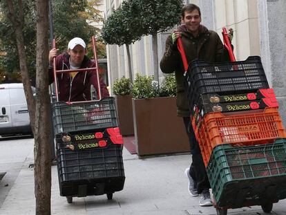 Dos jóvenes acarrean cestos de hortalizas. 