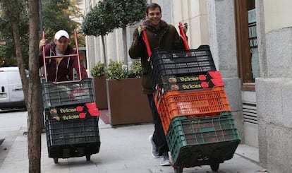 Dos jóvenes acarrean cestos de hortalizas. 